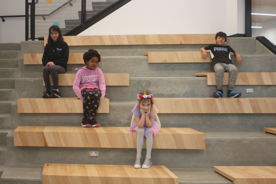 Paige, Naya, Ruby and Masseo stop for a photo in the tiered seating near the Skwo:wech Elementary School main entrance.