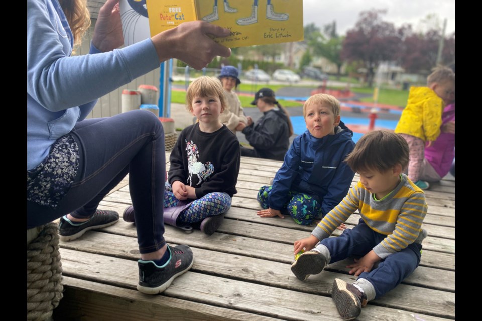 Sadie, aged four-and-three-quarters, Ewan, 3 and Thomas, 3, are an attentive audience for Nicole Marshall's story session during SD40's outdoor StrongStart session at Hume Park on Monday.