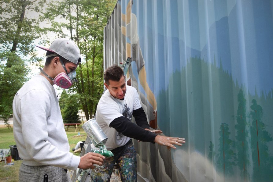 Artist Todd Polich, right, gives Take a Hike student Sasha Ruban pointers on painting a storage container in 2015.