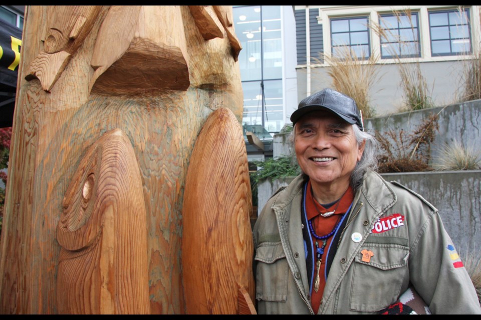 Master Squamish Nation carver Xwalacktun Rick Harry poses with a house post he carved that now stands at the entrance of the Burnaby school board office. 