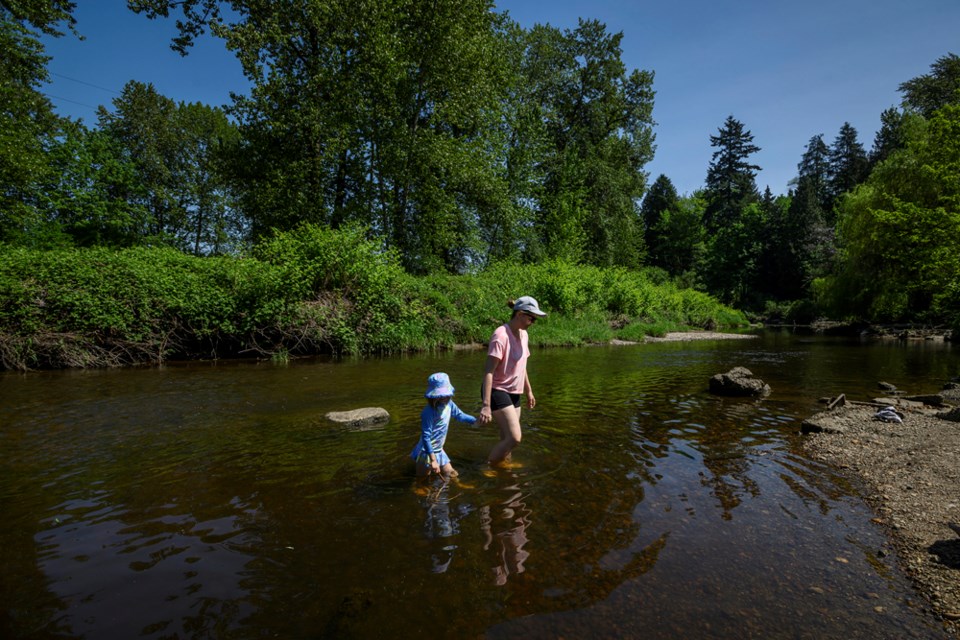 Klara Hovjacky cools off in in the Brunette River with daughters Ellie and Anna on Sunday.