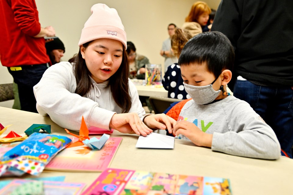 Volunteer Nanako Matsumoto and Liam Chen, 7, create origami during the Family Day festivities at the Nikkei Centre.