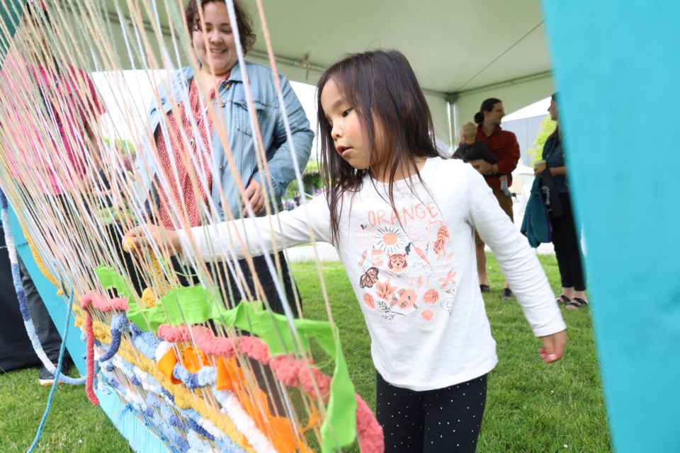 Four-year-old Sarenity Desjarlais-Cahoose weaves at the Burnaby Village Museum booth on National Indigenous Peoples Day in Burnaby.