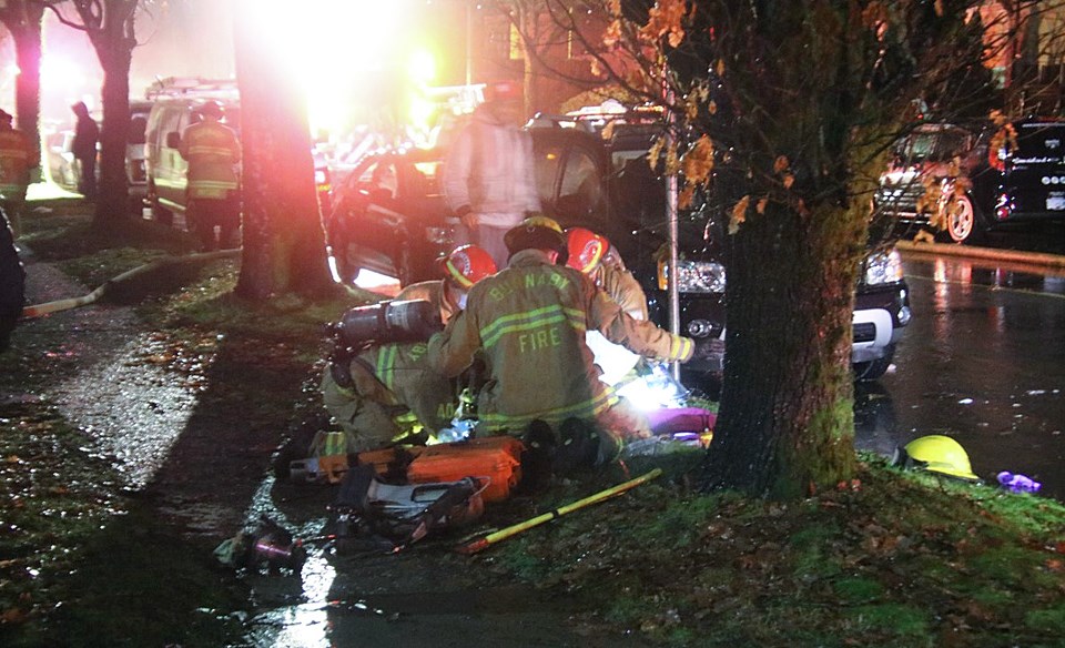 Firefighters work to revive a woman carried from a burning Pender Street apartment building early Thursday morning.