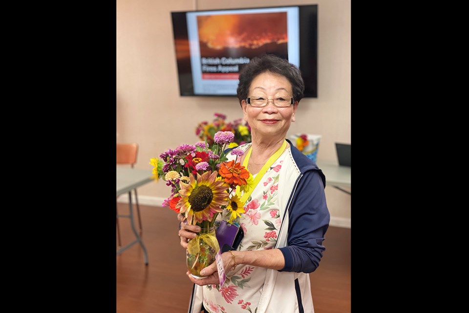 Mrs. Ma, 83, presents a floral arrangement she made with her Gaia Cares' Adult Day program in Burnaby, part of a near $5,000 fundraising campaign for B.C. wildfire relief.