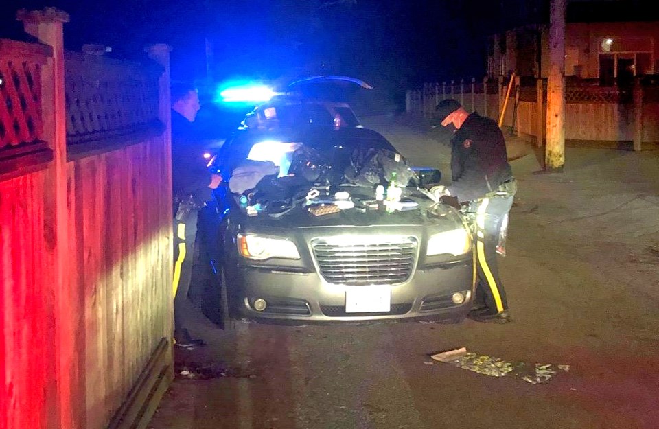 Burnaby RCMP officers sort nearly two pounds of suspected illicit drugs, weapons and other items after a traffic stop in Burnaby early Tuesday morning.