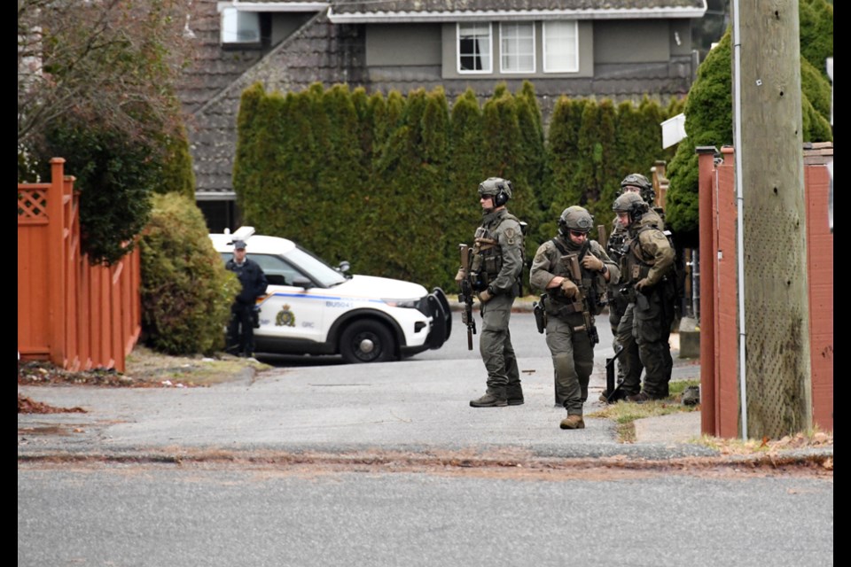 Lower Mainland Emergency Response Team members  surround a home on Portland Street in Burnaby Tuesday.