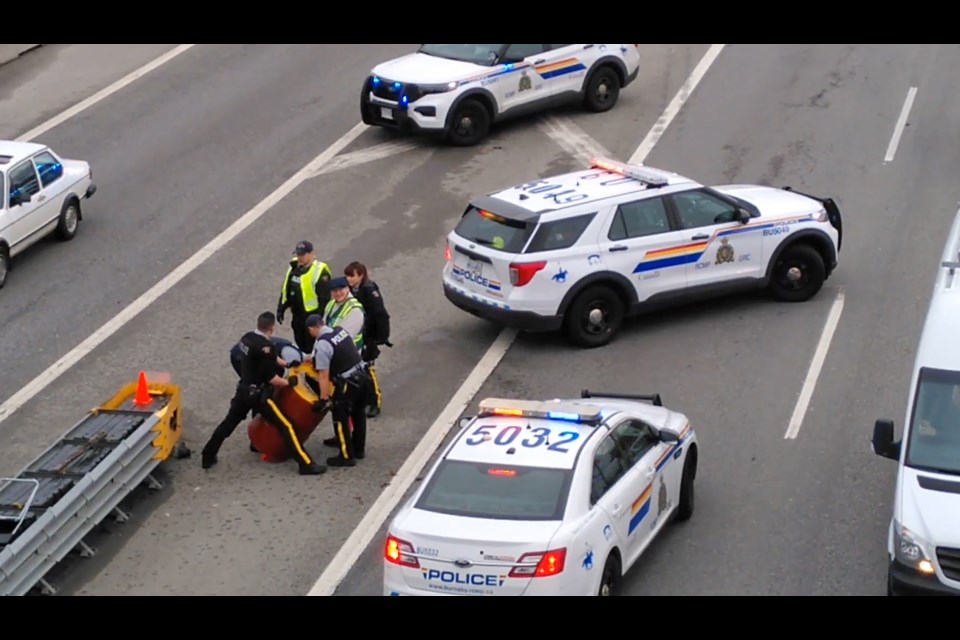 Police detain an anti-logging protester who locked himself to a concrete-filled barrel on Highway 1 in Burnaby Wednesday. 