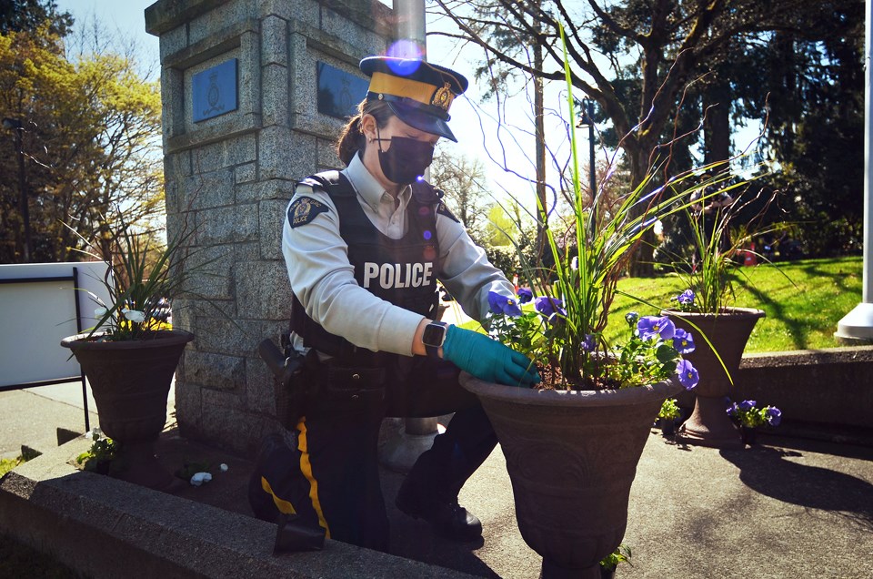 Cpl. Laura Hirst plants one of 22 flowers planted at the Burnaby RCMP detachment Monday morning to honour the victims of the Nova Scotia shootings in April 2020.