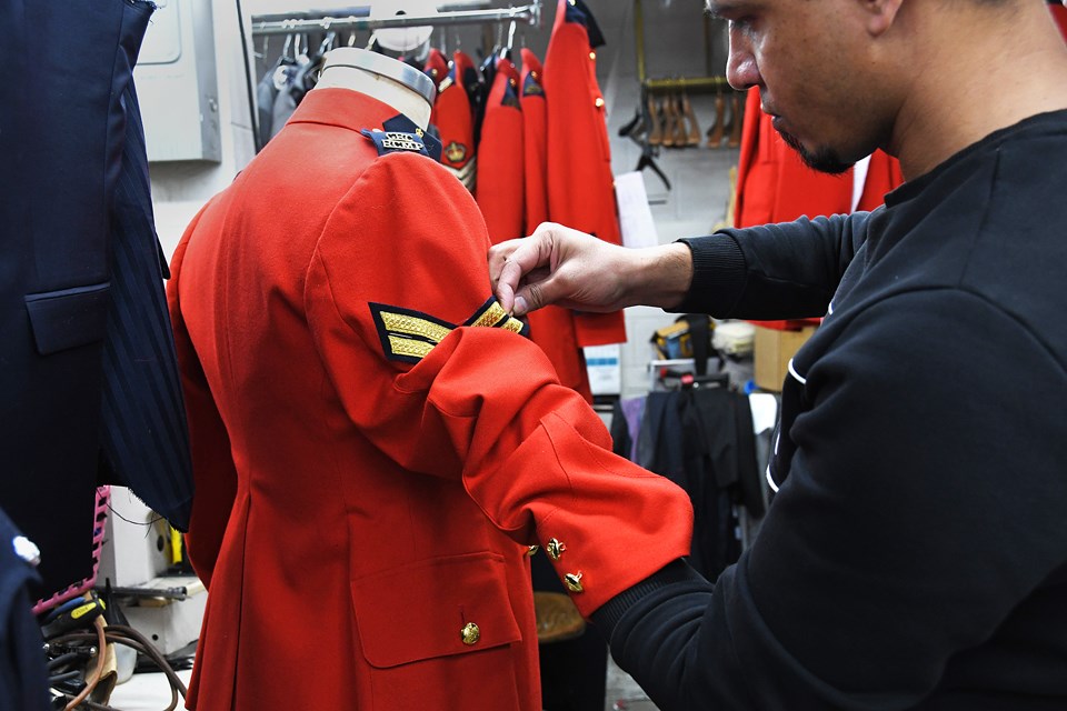 Tailor Hawad Amini pins a new badge onto an RCMP coat at Seville Tailors in Burnaby Tuesday. 