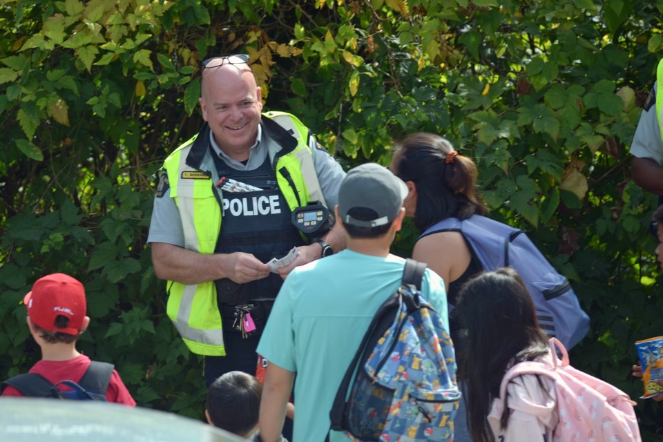 Reserve Const. Tony Bernard hands out McDonald's ice cream coupons and pencils to students at Forest Grove Elementary School Wednesday.