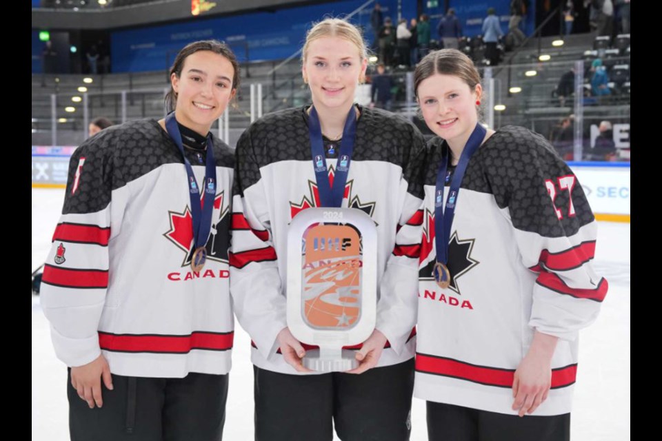 Chloe Primerano (#8), an alumna of Burnaby Winter Club,  poses with Canada teammates with her bronze medal and the third-place trophy at the 2024 IIHF Under-18 Women's World Hockey Championships in Zug, Switzerland.