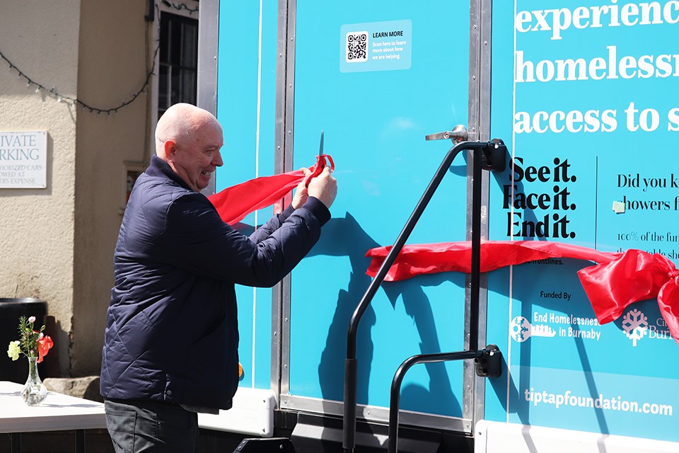 Burnaby Mayor Mike Hurley cuts the ribbon on the mobile showers. 