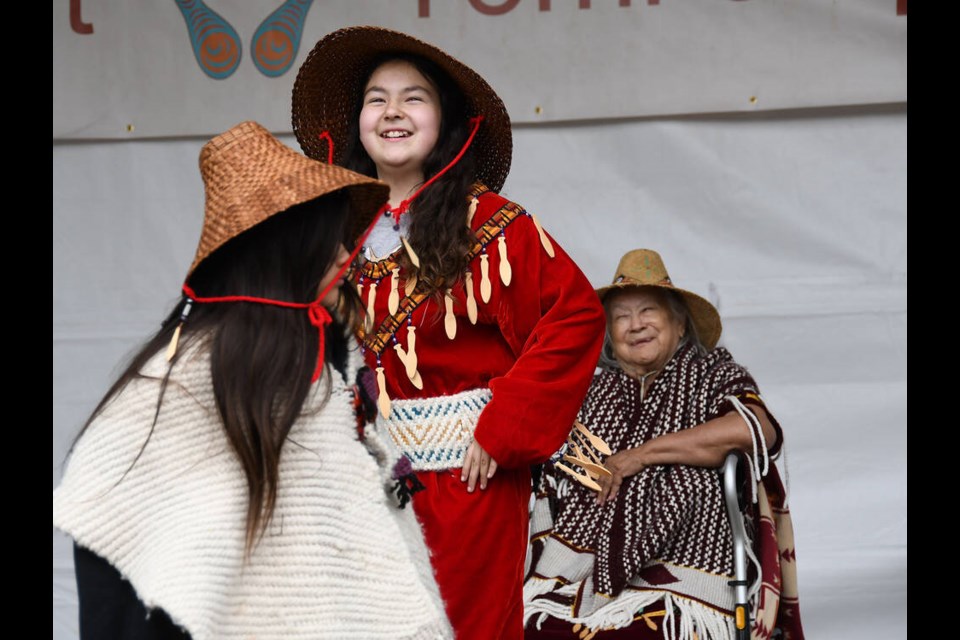 Lilly Wyss (centre) dances with Kamaya Leo (left) of the Chesha7 iy lha muns group at the National Indigenous Peoples Day event in Burnaby. Matriarch Kultsia Barbara Wyss (right) shared stories and histories of the Squamish Nation. Photo Lauren Vanderdeen/Burnaby Now.