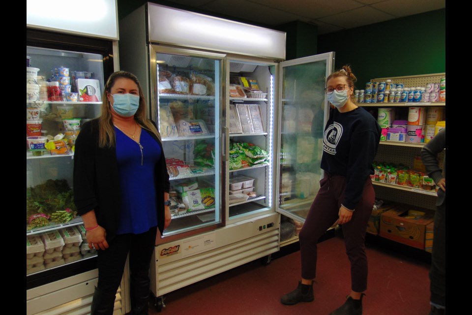 Sarah Tooze, from left, food bank volunteer Carolyn Holmes in the Community Pantry at the Cambridge Food Bank.                              