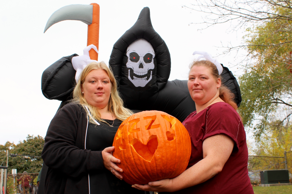 Amber (left) and Tammy Masters, the sister and mother of Elizabeth Ariel, hold a pumpkin with her nickname "Izzy" carved in it. The prop will be part of the haunted house being planned to honour her on Halloween.