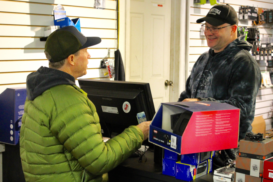 Clifford Vanclief (right) interacts with a customer at The Hub Bicycle Shop on its final day of in-store service.