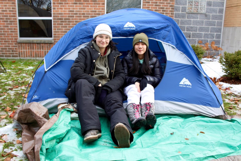 Tatiana English and Danielle Tejero sit in the tent they spent the night in overnight Thursday during a sleep out at Monsignor Doyle Catholic Secondary School to raise awareness and funds for homelessness.