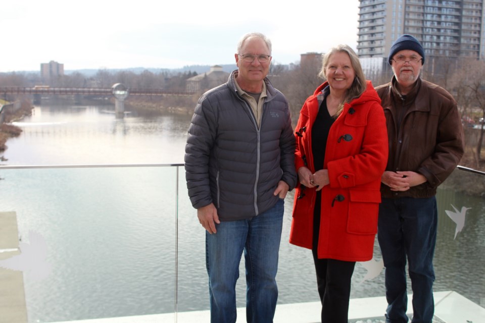 Rob Brisson (left), Ingrid Talpak and Ray Martin stand on the balcony of the Old Post Office Idea Exchange overlooking the river. They're helping organize an event in May to recognize the 50th anniversary of the 1974 Cambridge flood.