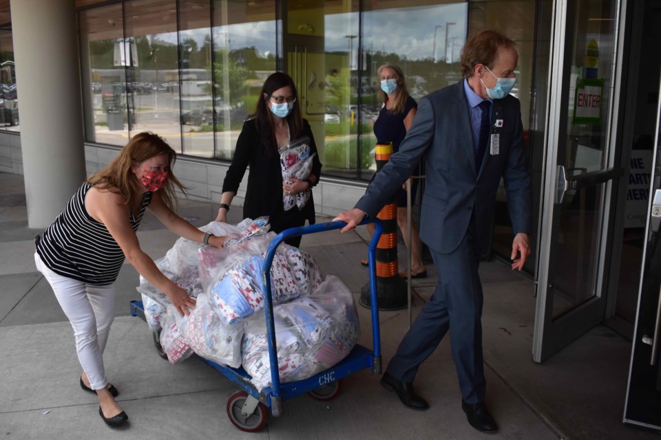 Dr. Winnie Lee, Corey Kimpson, chair of the Cambridge Memorial Hospital patient and family advisory council and Patrick Gaskin, president and CEO at Cambridge Memorial Hospital bring the final donation of masks into the hospital.