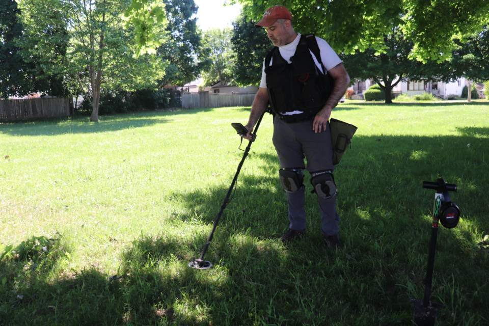 Chris Busby waves his metal detector over the ground in Lincoln Park in Cambridge.