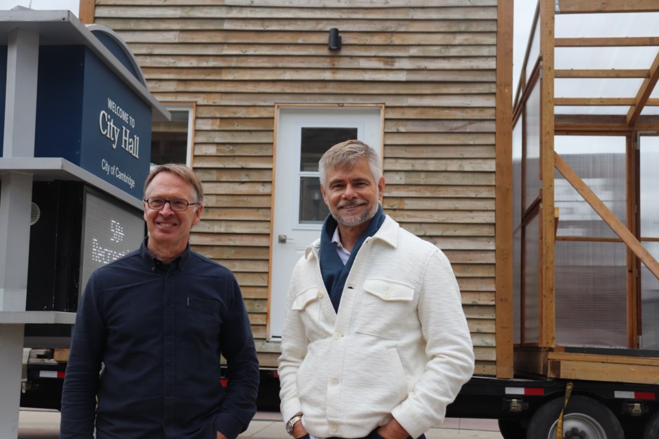 University of Waterloo architecture professor John McMinn (left) and  deputy city manager of community development Hardy Bromberg pose in front of the tiny home before it's unloaded into Civic Square.
