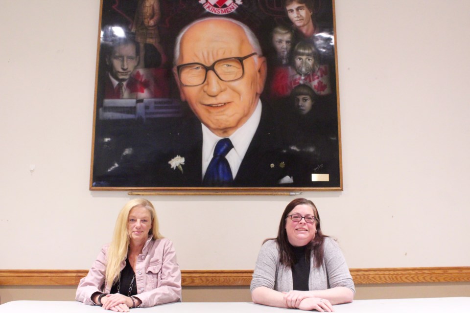 Kin Club of Preston president Sylvia Wagner (left) and treasurer Melissa Whetham sit in front of a mural of Kin Club of Canada founder Harold Rogers in their hall on Hamilton Street. The building is set to be demolished as part of the Preston Auditorium expansion.