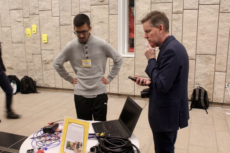 St. Benedict Catholic Secondary School student Syed Hashmi explains his automated gardening system to Brian Rodnick of the Cambridge Chamber of Commerce