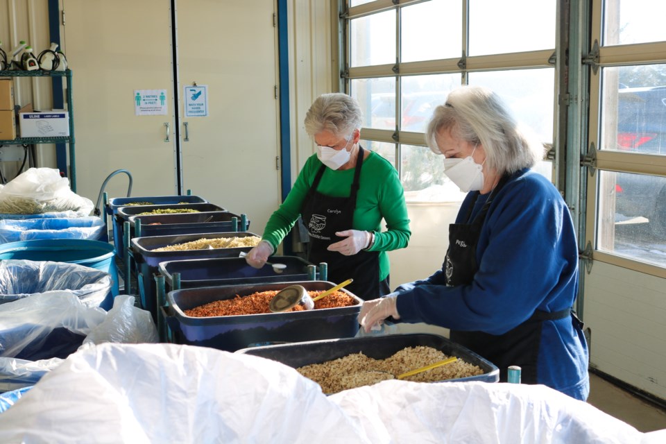 Volunteers scoop dehydrated vegetables into bags.