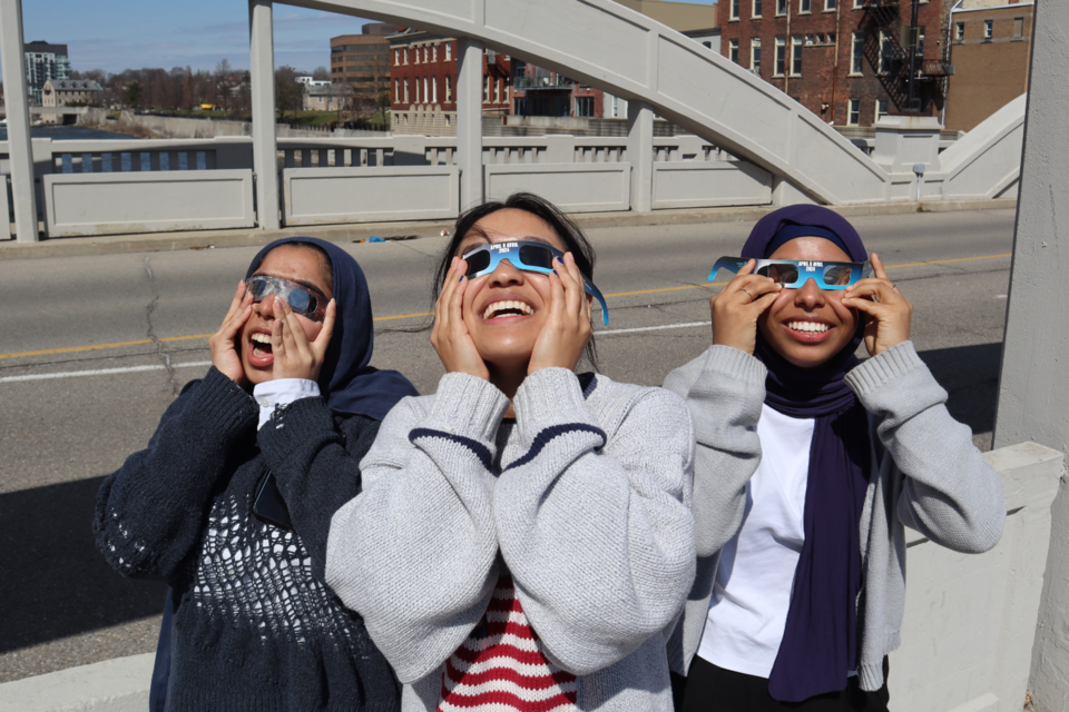 Friends and students from the University of Waterloo School of Architecture Aatiquah, Kyra and Aiisha watch the eclipse from the Main Street bridge in Galt.