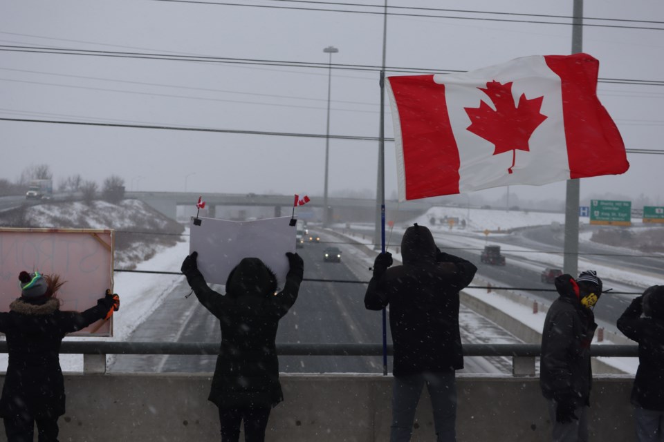 Supporters of the so-called 'Freedom Rally' truck convoy show their support as it drives through Cambridge on Highway 401 Thursday afternoon. About 50 people gathered on the Fountain Street overpass.
