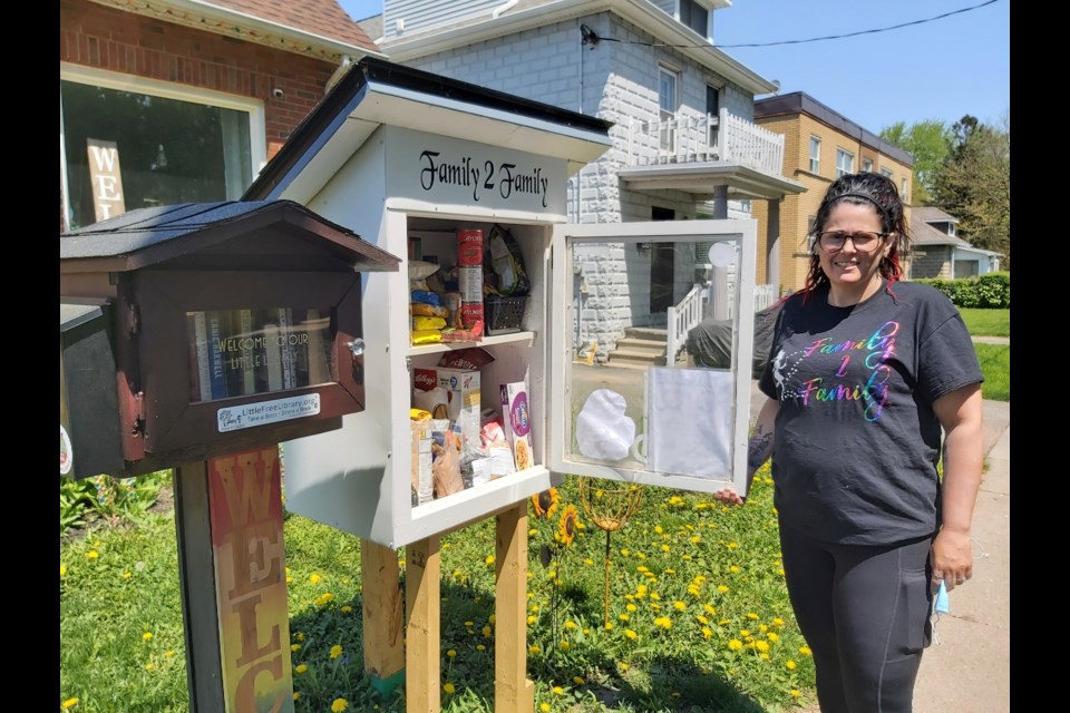 Kristin Percival, pictured next to a food pantry at 446 Argyle St. S., says due to high demand she has to fill the cupboard thrice a day. 