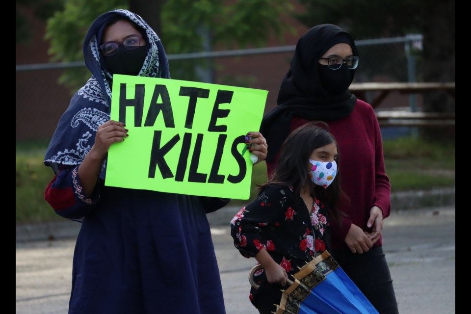 A woman holds a sign condemning hate at the Islamic Centre of Cambridge on Monday during a rally in support of the Afzaal family of London.