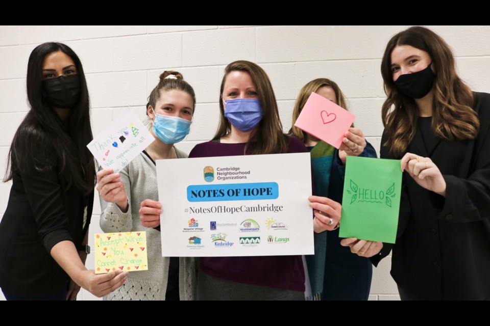 Members of the Cambridge Neighbourhood Organizations hold up cards made for the Notes of Hope campaign.