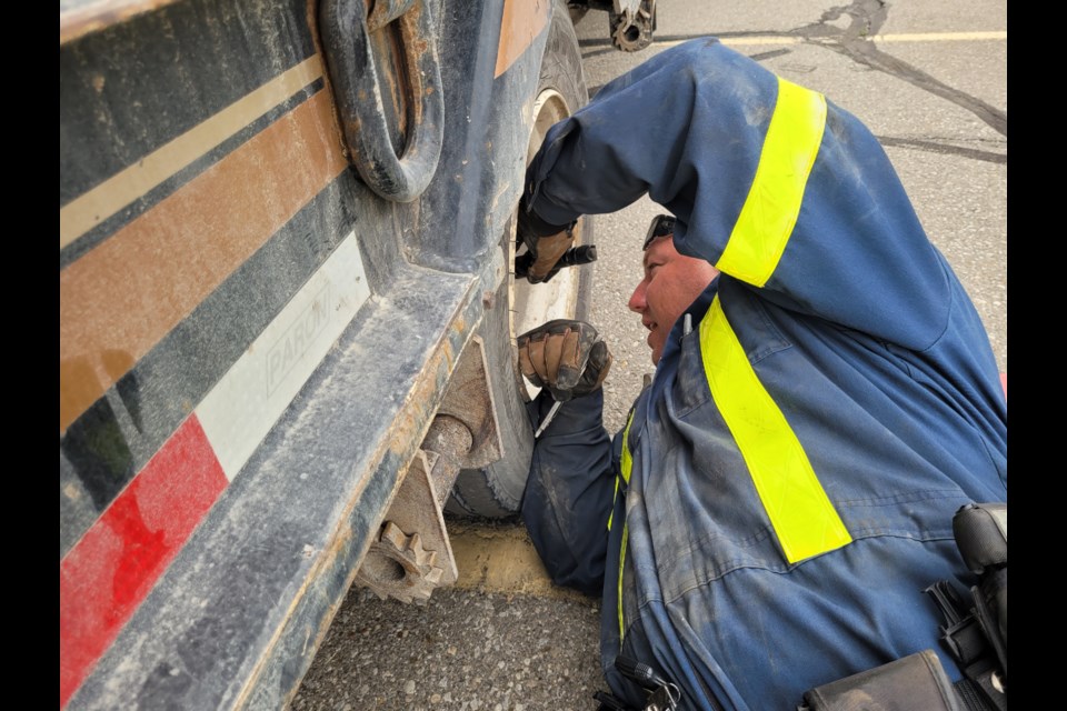 Guelph Police Service Const. Tim Paneghel, who is certified with the Commercial Vehicle Safety Alliance, inspects a wheel on a commercial truck during an inspection blitz at the Cambridge campus of Conestoga College on Thursday.