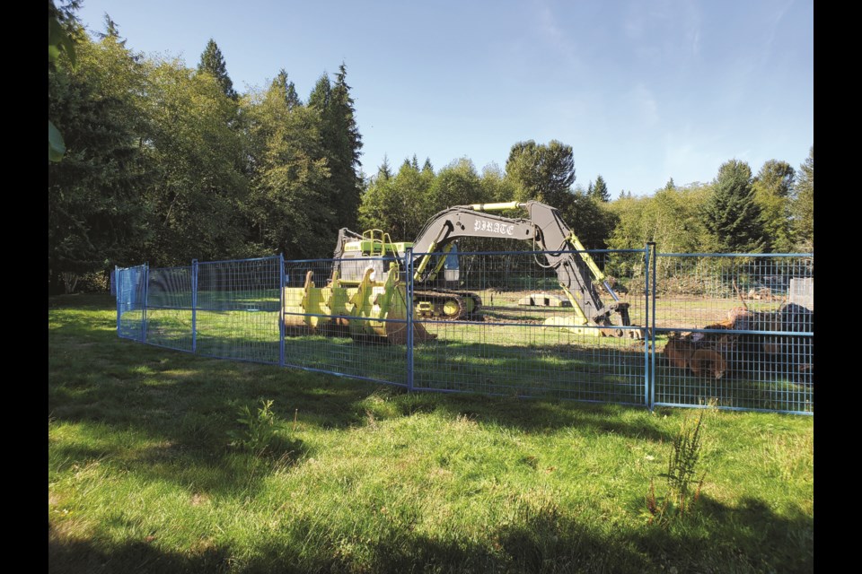 An excavator sits motionless behind security fencing at Gibsons’ White Tower Park. The construction of a storm water retention pond is on hold pending an archeological assessment after the discovery of an artifact on the site.