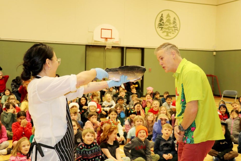 Fisherman's Market's Emmas Tsao holds up the fish for Cedar Grove Elementary principal Jamie Sadler to kiss. 