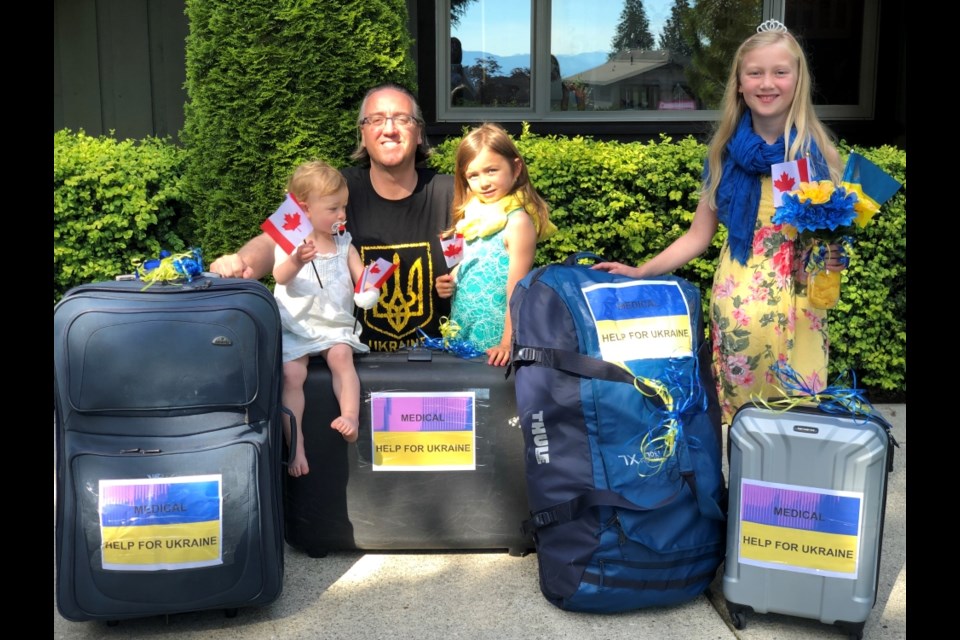 Milos Pospisil with his three daughters and the donated supplies he brought to Ukraine from B.C.