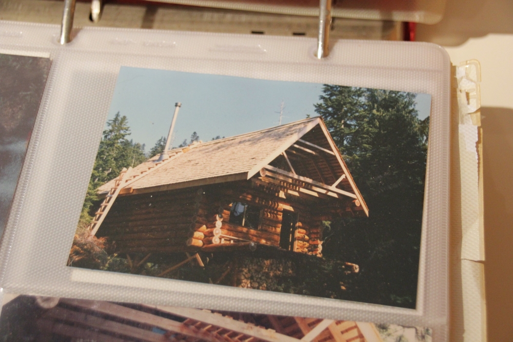 An old photo of a log cabin being built.