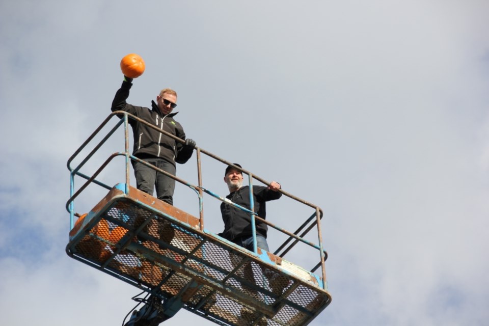 The RentalEquip crew throws pumpkins down into the loaned container for a smashing fundraiser.