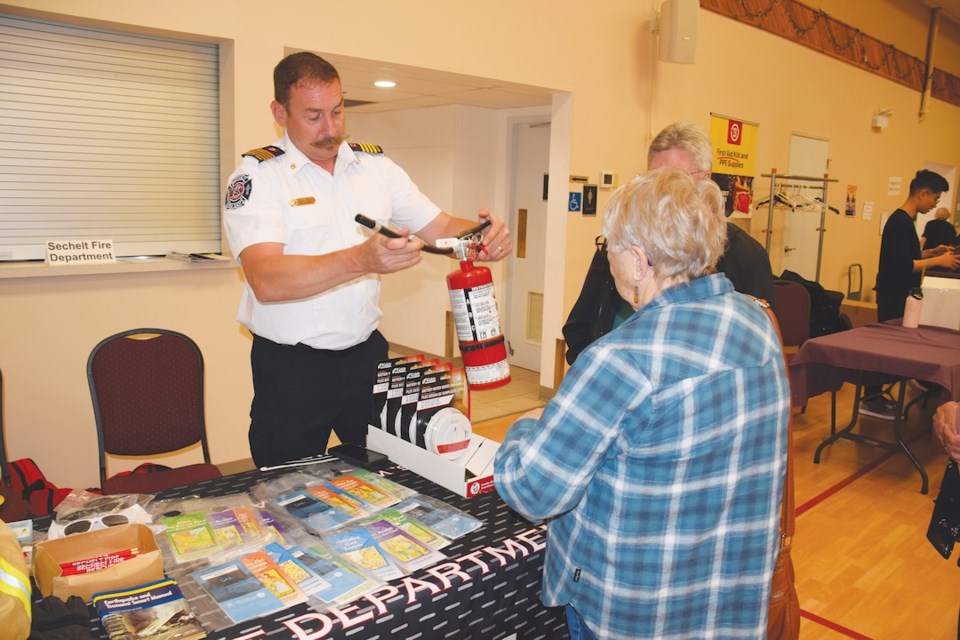 Steven Achterberg, deputy chief of prevention for the Sechelt Fire Department, demonstrates how to use a fire extinguisher. Sechelt Mayor John Henderson is beside Achterberg. 
