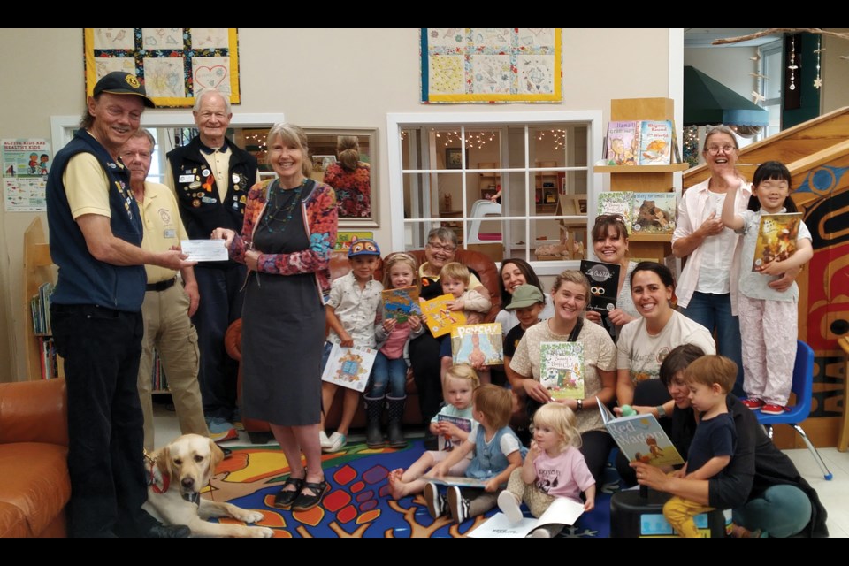 Sunshine Coast Lions (left to right Bill Conway, Tony Stroud, Al Hailey and Linda Stroud (seated) present Kirsten Deasey, SD46 District Principal of Learning, Innovation & Child Care, with cheques for a total of $4,000 to go toward the Imagination Library Program. Also in the picture are parents and children enjoying books from the Imagination Library program, with SD46 staff Sarah Stenzel and Marilyn Downey. 