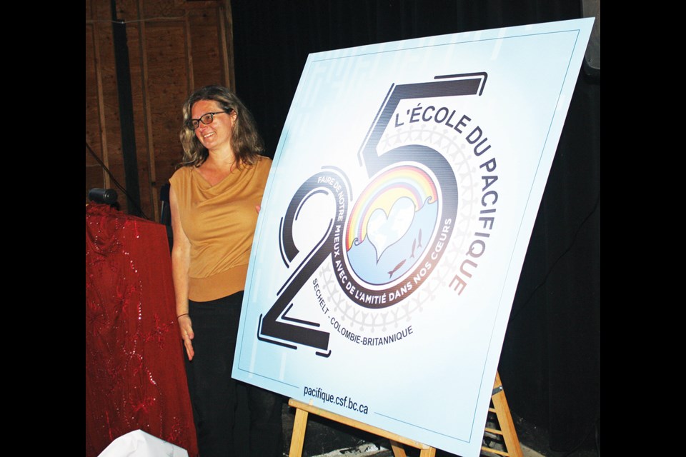 Principal Mélanie Vallières unveils the school’s new logo. The words read “To do our best with friendship in our hearts.”