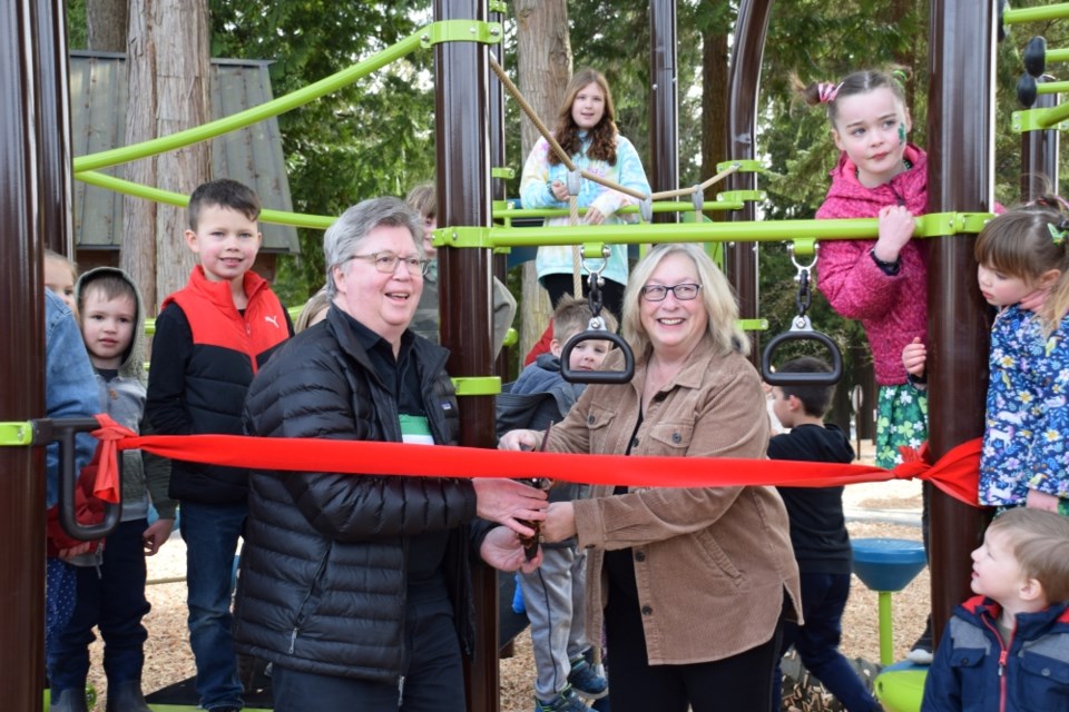 Mayor John Henderson and Darnelda Siegers cut the ribbon on the new Hackett Park playground as local children excitedly wait. 