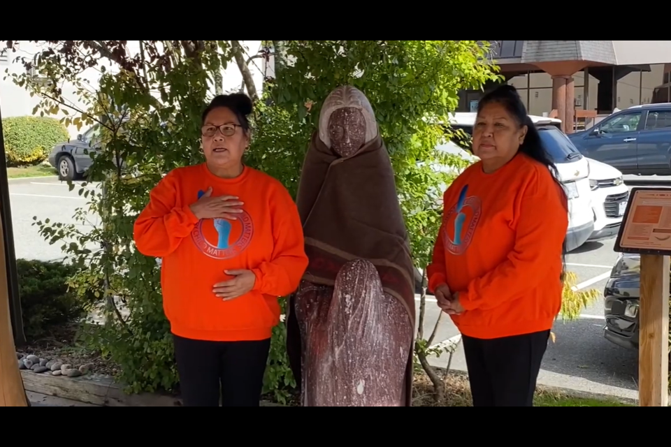 Elders Angelene Valerie Bourne and Audrey Joe place a blanket on the shoulders of the Grieving Mother statue as they speak on the National Day for Truth and Reconciliation.