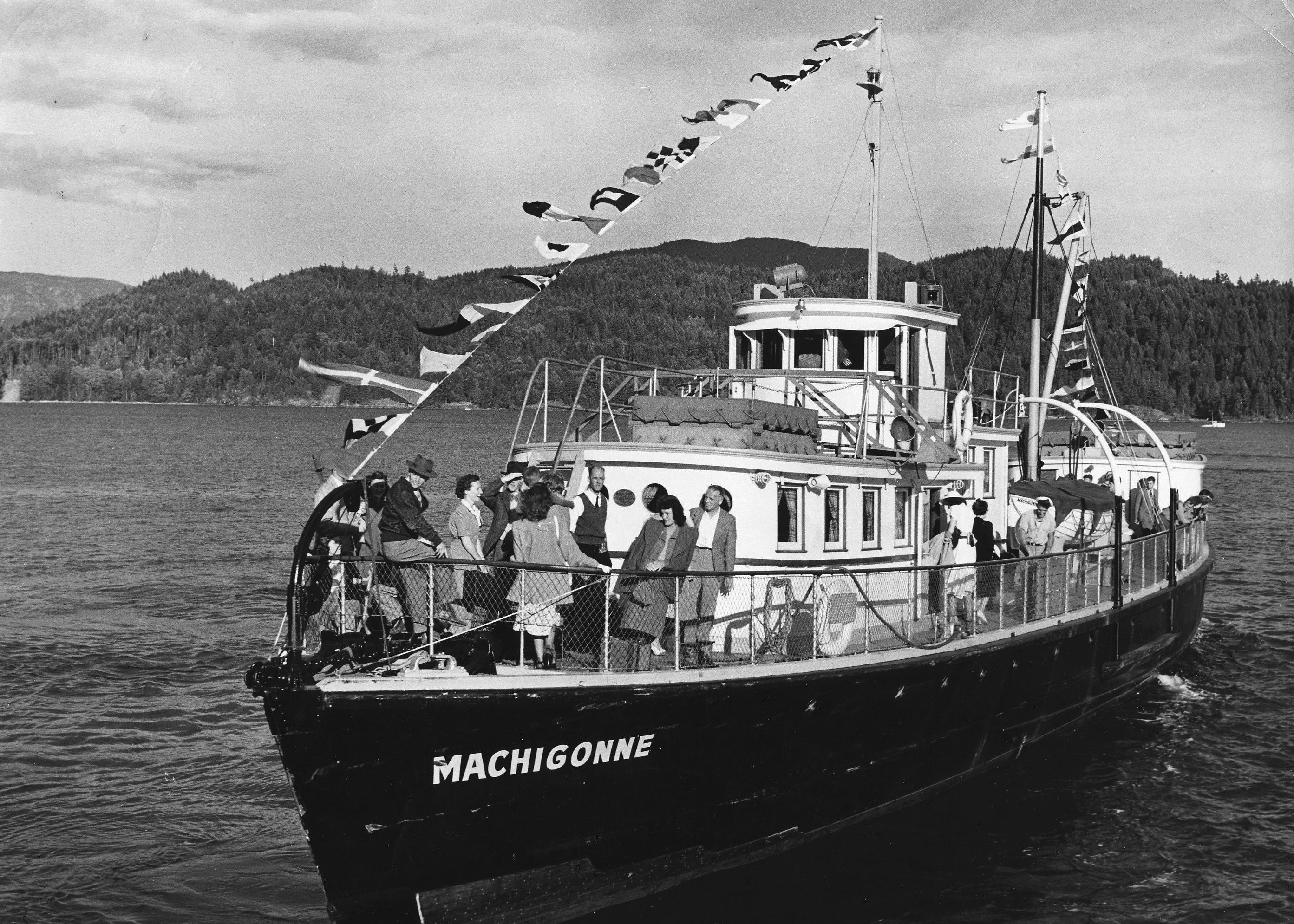 A black and white photo shows people standing on the bow of a ferry.