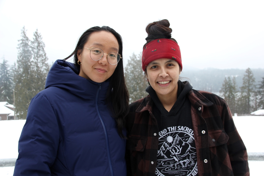 Two women stand together outdoors.