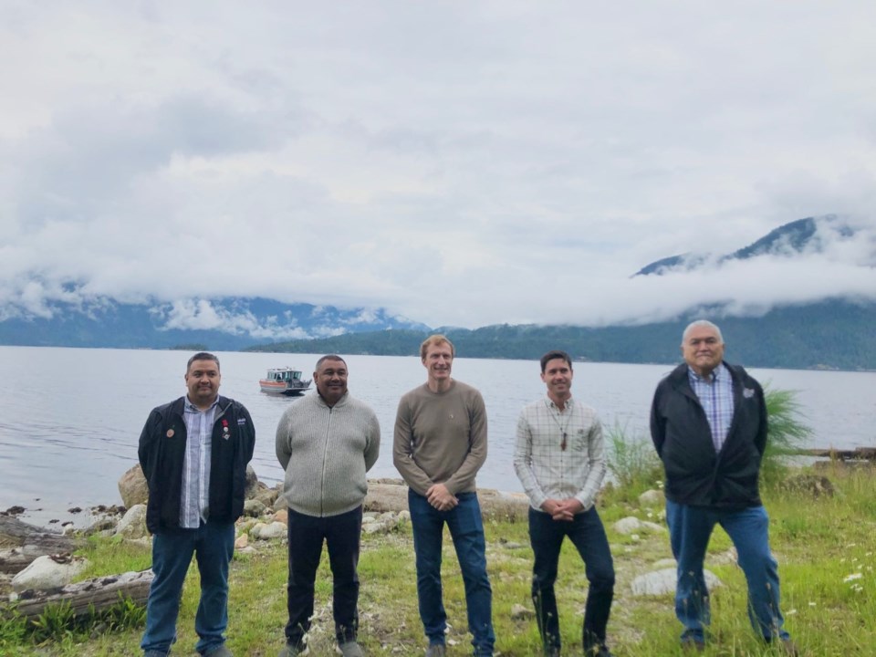 Five men standing on a seaside piece of land. 