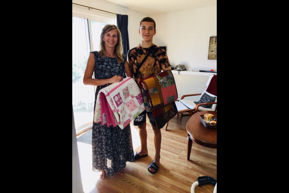 Uliana and Danylo Haidaienko display handmade quilts donated to Ukrainian newcomers by members of the Sunshine Coast Quilters’ Guild. 