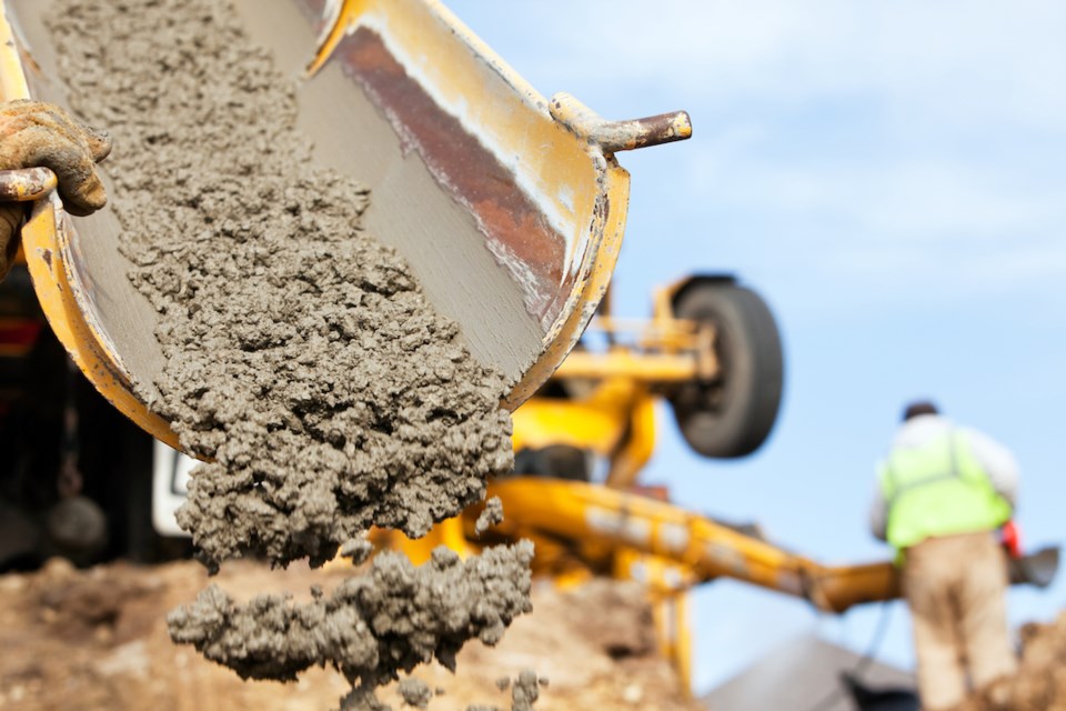 a-construction-worker-is-guiding-a-cement-mixer-truck-chute-as-concrete-is-being-offloaded-for-a-new-house-footing